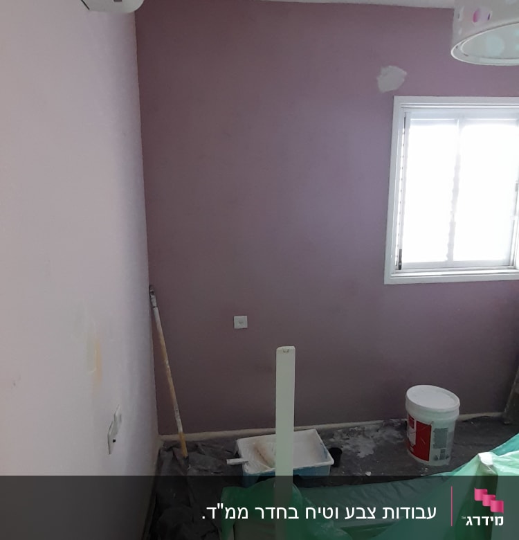 חדר עם קיר צבוע, דלי צבע ומברשת